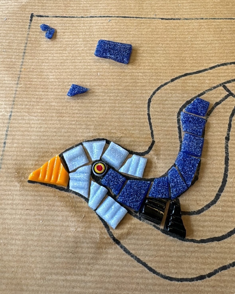 Close-up of the head of the bird stencil with irregularly-shaped blue and black tiles 